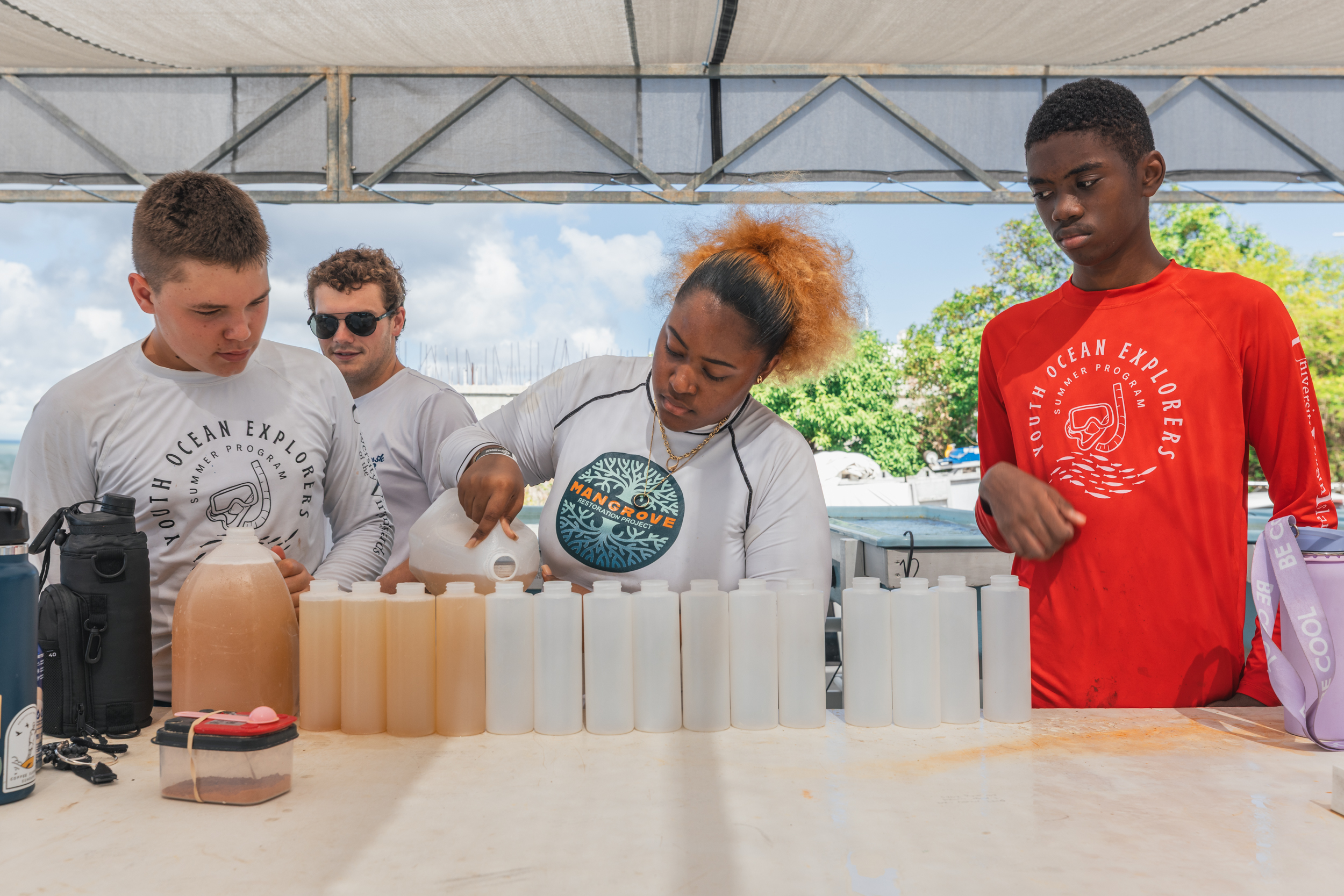 Youth Ocean Explorers counselors and participants prepare a bottle of coral food to feed the corals in their nursery. Photo: Dan Mele